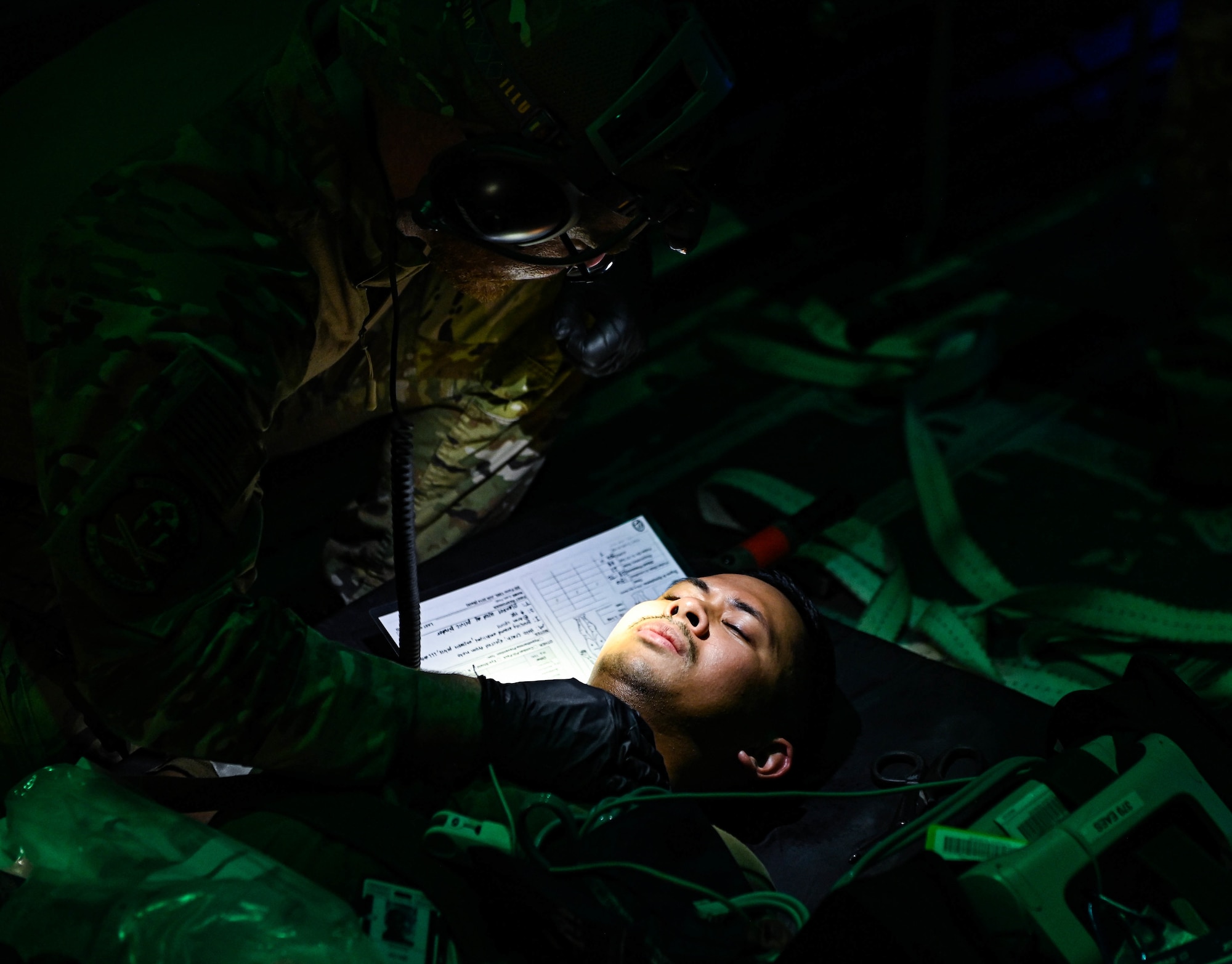 U.S. Air Force Capt. Aaron Porter, a 379th Expeditionary Medical Group nurse, administers care to a patient during an exercise Aug 4, 2022 at Al Udeid Airbase, Qatar. The medical staff trained in low light conditions on board a C-130 Hercules. (U.S. Air National Guard photo by Master Sgt. Michael J. Kelly)