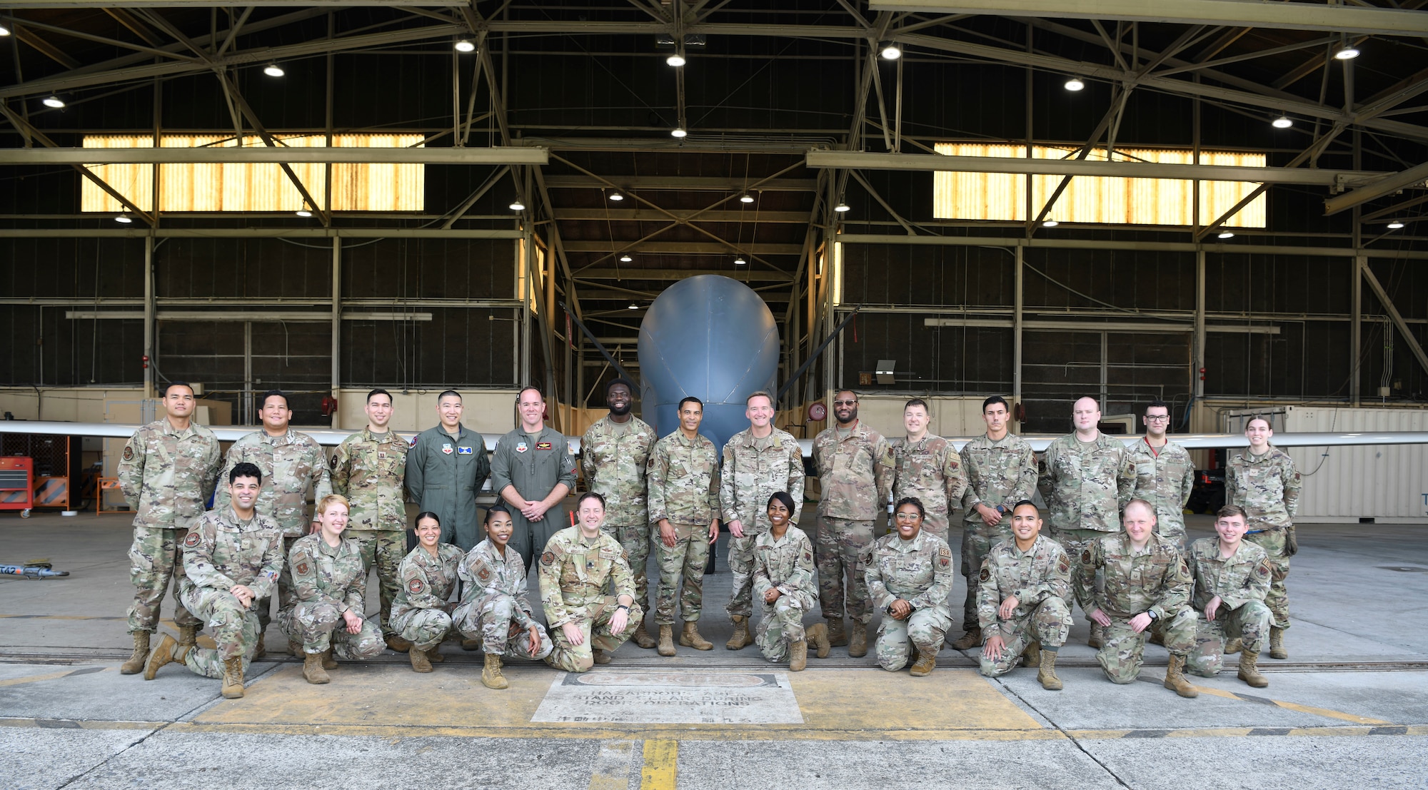 Airmen pose for a group photo in front of an RQ-4 Global Hawk