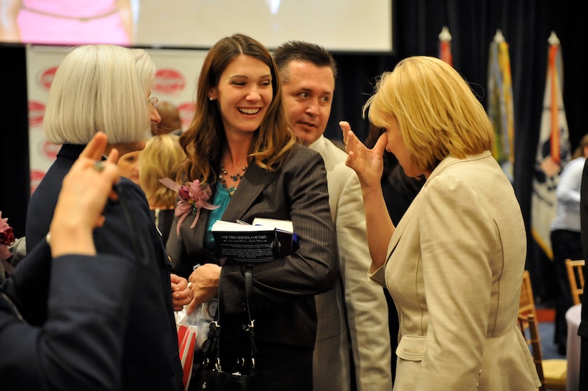 A woman smiles as she socializes with a group of people.