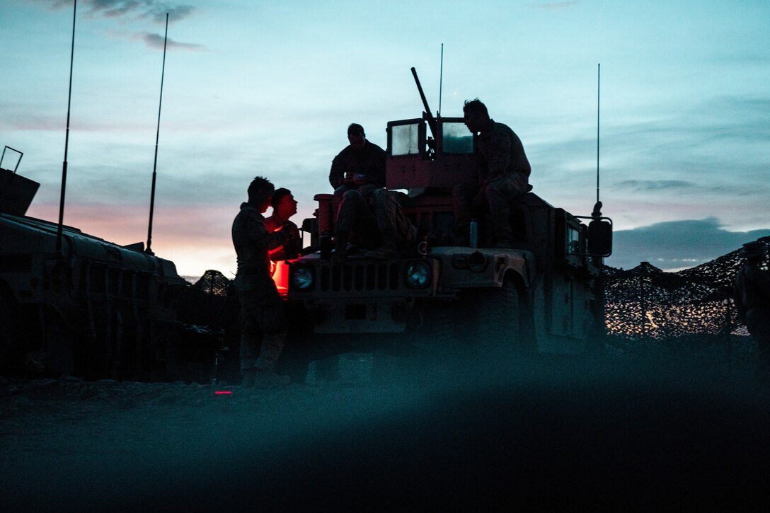Marines gather around  a military vehicle at dawn.