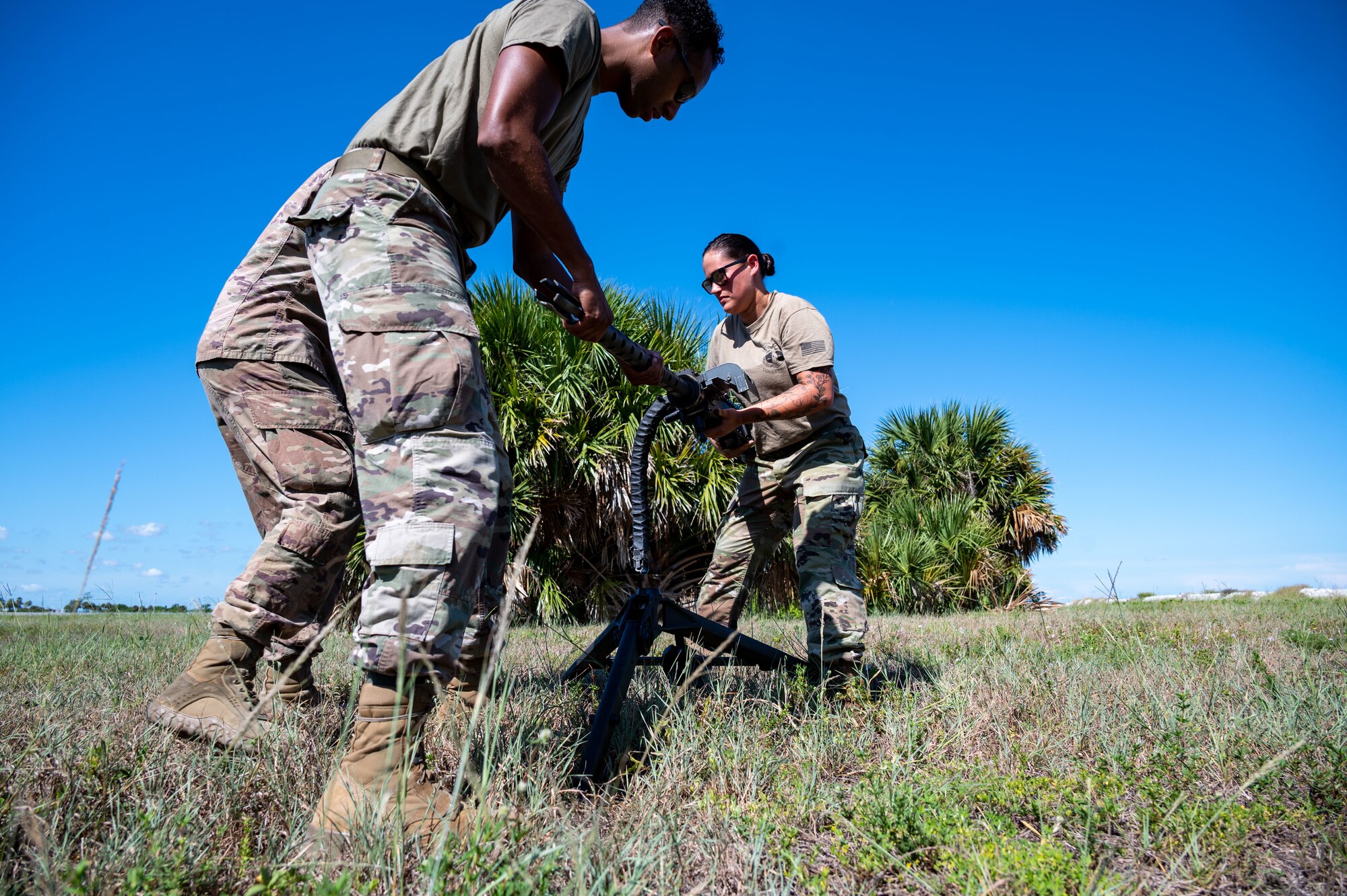 Senior Airman Andrew Hernandez and Staff Sgt. Taylor Bender, 920th AMXS weapons load crew members, work alongside Technical Sgt. Tony Blaile, 920th Aircraft Maintenance Squadron weapons expeditor, to install a GAU-18 machine gun from a 920th Rescue Wing HH-60G Pave Hawk helicopter onto an M-205 tripod mount Aug. 6, 2022 at Patrick Space Force Base, Florida. (U.S. Air Force photo by Master Sgt. Kelly Goonan)