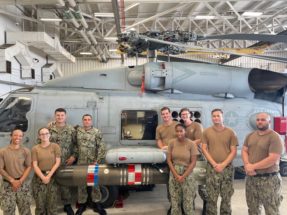 Sailors posing next to a helicopter