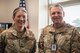 Two military members stand next to each other and pose for a photo inside of an office.