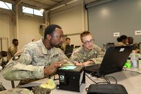 Spc. Neal Long, left, 42 alpha, 304th Military Police Battalion, Headquarters and Headquarters Company, Nashville, Tennessee learns how to in-process fingerprints during biometric training at Pershing Strike.