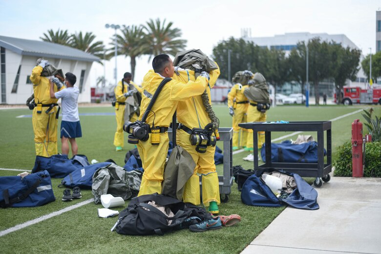 The 61st Medical Squadron help each other suit up before contaminated patients arrive.