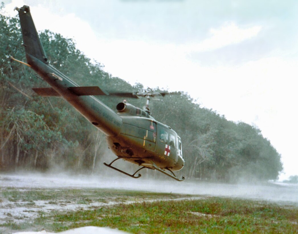 A helicopter hovers above a grass field.