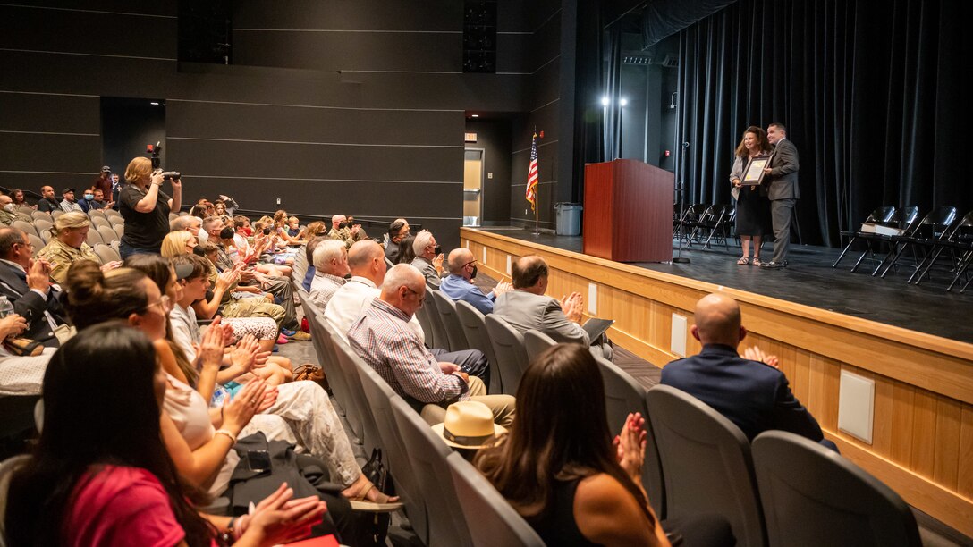 Pamela Balch, a representative of Assemblyman Tom Lackey, presents a certificate to Kevin Cordes, Muroc Joint Unified School District Superintendent, inside the new performing arts theater at Desert Jr./Sr. High School on Edwards Air Force Base, California, Aug. 9. (Air Force photo by Giancarlo Casem)