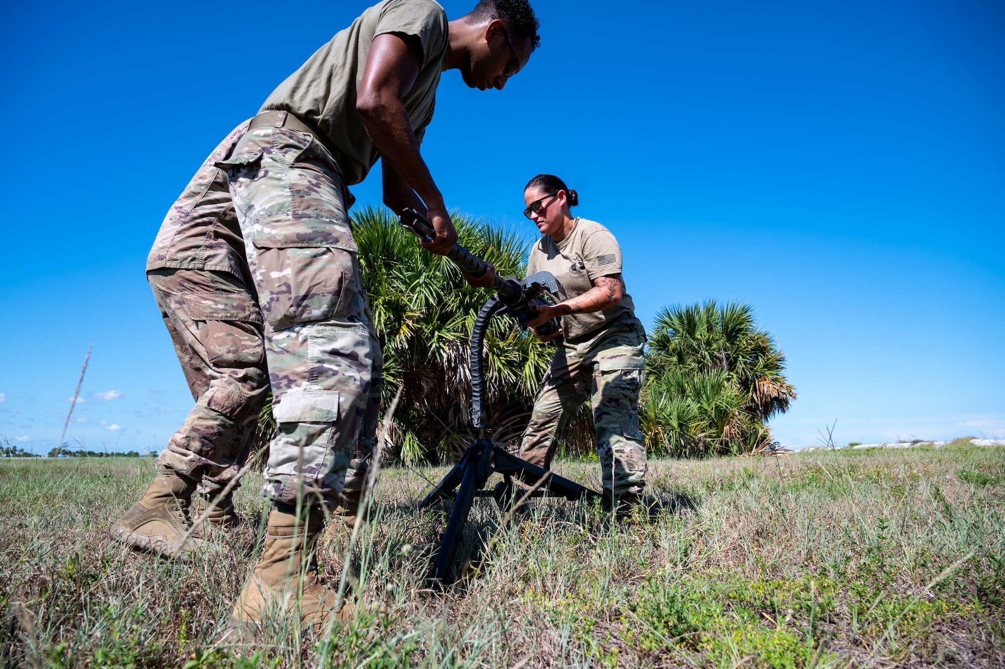 Senior Airman Andrew Hernandez and Staff Sgt. Taylor Bender, 920th AMXS weapons load crew members, work alongside Technical Sgt. Tony Blaile, 920th Aircraft Maintenance Squadron weapons expeditor, to install a GAU-18 machine gun from a 920th Rescue Wing HH-60G Pave Hawk helicopter onto an M-205 tripod mount Aug. 6, 2022 at Patrick Space Force Base, Florida. (U.S. Air Force photo by Master Sgt. Kelly Goonan)