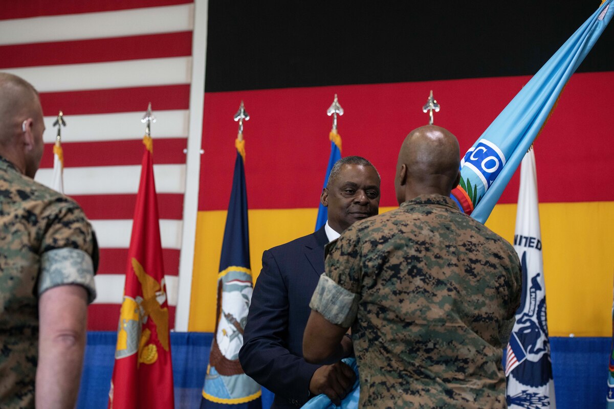 Two men face each other holding a flag.