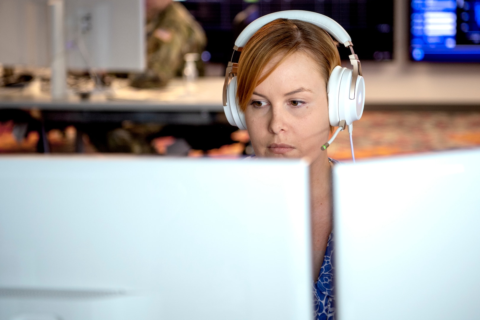 Woman with headset staring at computer screens