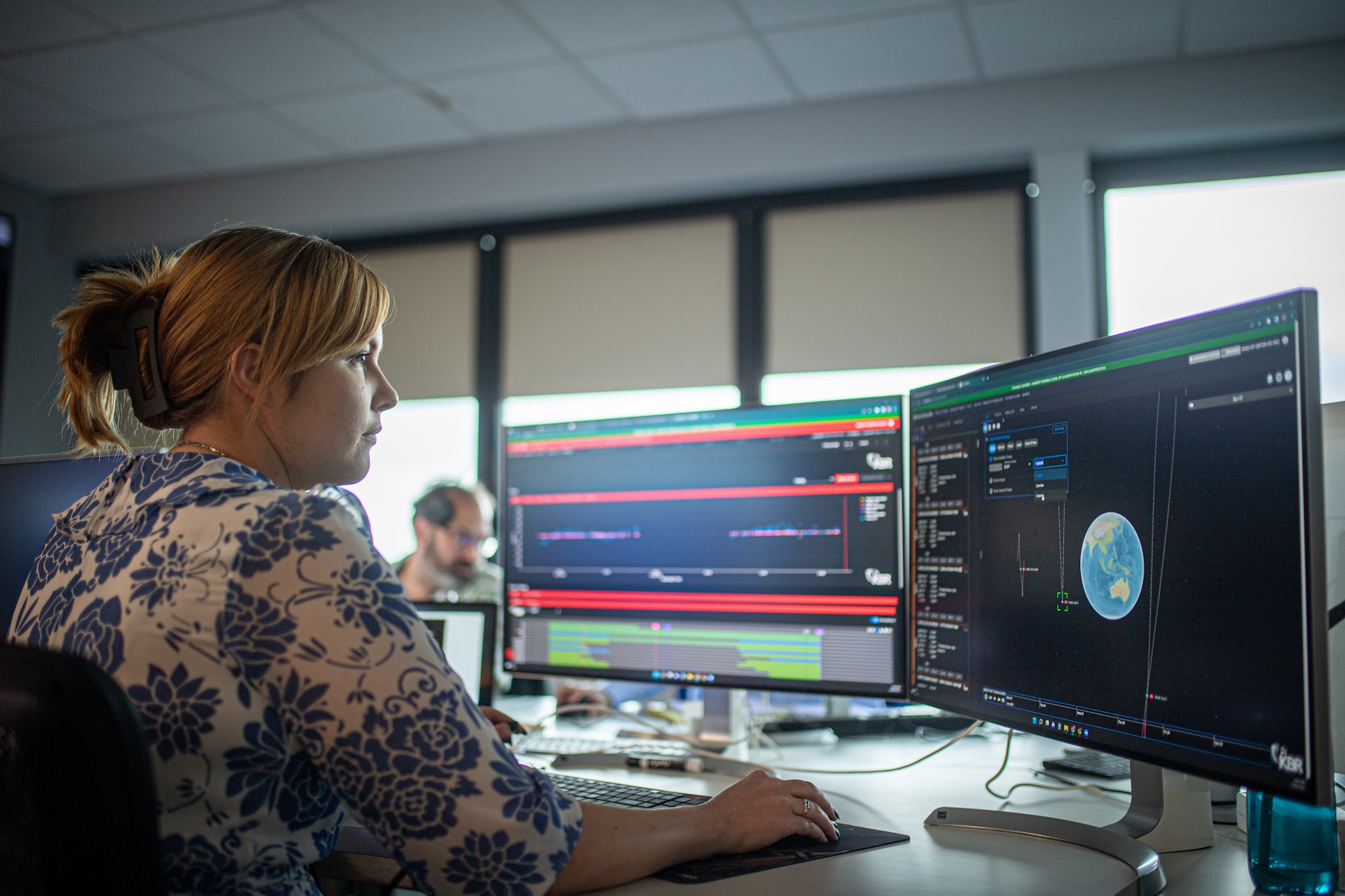 Woman looking at computer screens while holding mouse