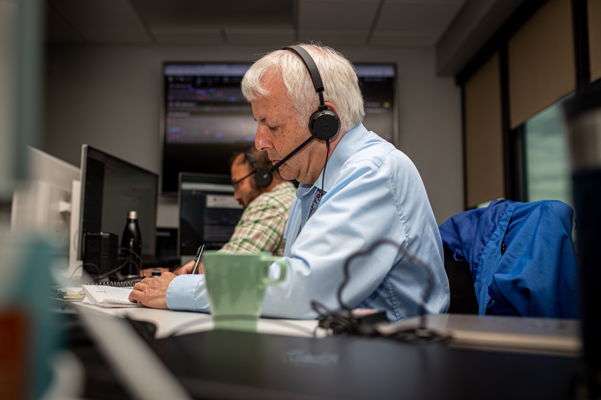 Man sitting at computer screen with headset on