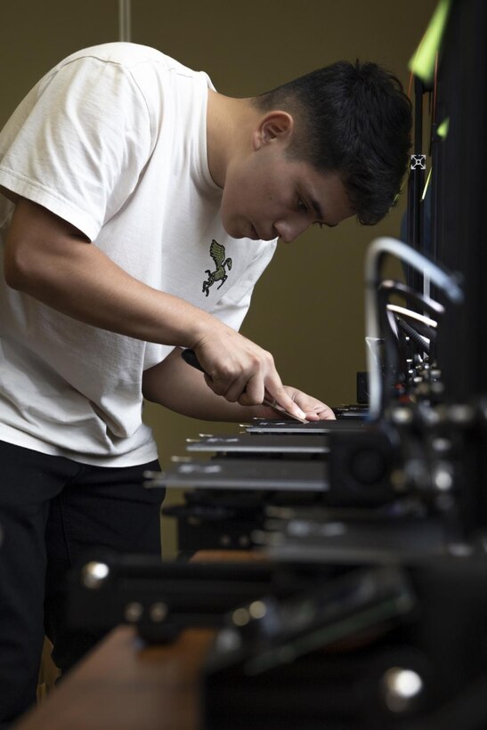 U.S. Marine Corps Cpl. Alexis Trejogarrido, a telephone systems/personal computer repairs technician with 7th Communication Battalion, III Marine Expeditionary Force Information Group, scrapes filament off of a 3D printer during Innovation Boot Camp (IBC) on Camp Hansen, Okinawa, Japan, Aug. 1, 2022. IBC was designed to teach Marines skills such as welding, 3D printing, coding, and programming to create innovative products for the Marine Corps and to test Marines’ critical thinking skills. Trejogarrido is a native of Mesa, Arizona. (U.S. Marine Corps photo by Sgt. Savannah Mesimer)