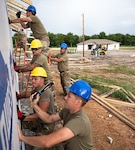 Members of the 126th Civil Engineer Squadron and 301st CES work together to install vapor wrap on a house before a rain storm comes, in Tahlequah, Oklahoma,  Aug. 5, 2022.