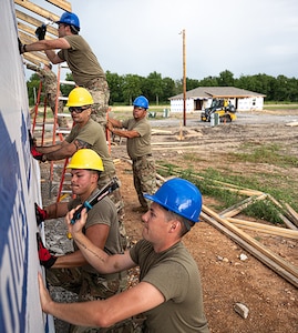 Members of the 126th Civil Engineer Squadron and 301st CES work together to install vapor wrap on a house before a rain storm comes, in Tahlequah, Oklahoma,  Aug. 5, 2022.