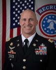 Soldier in dress uniform in front of flags.