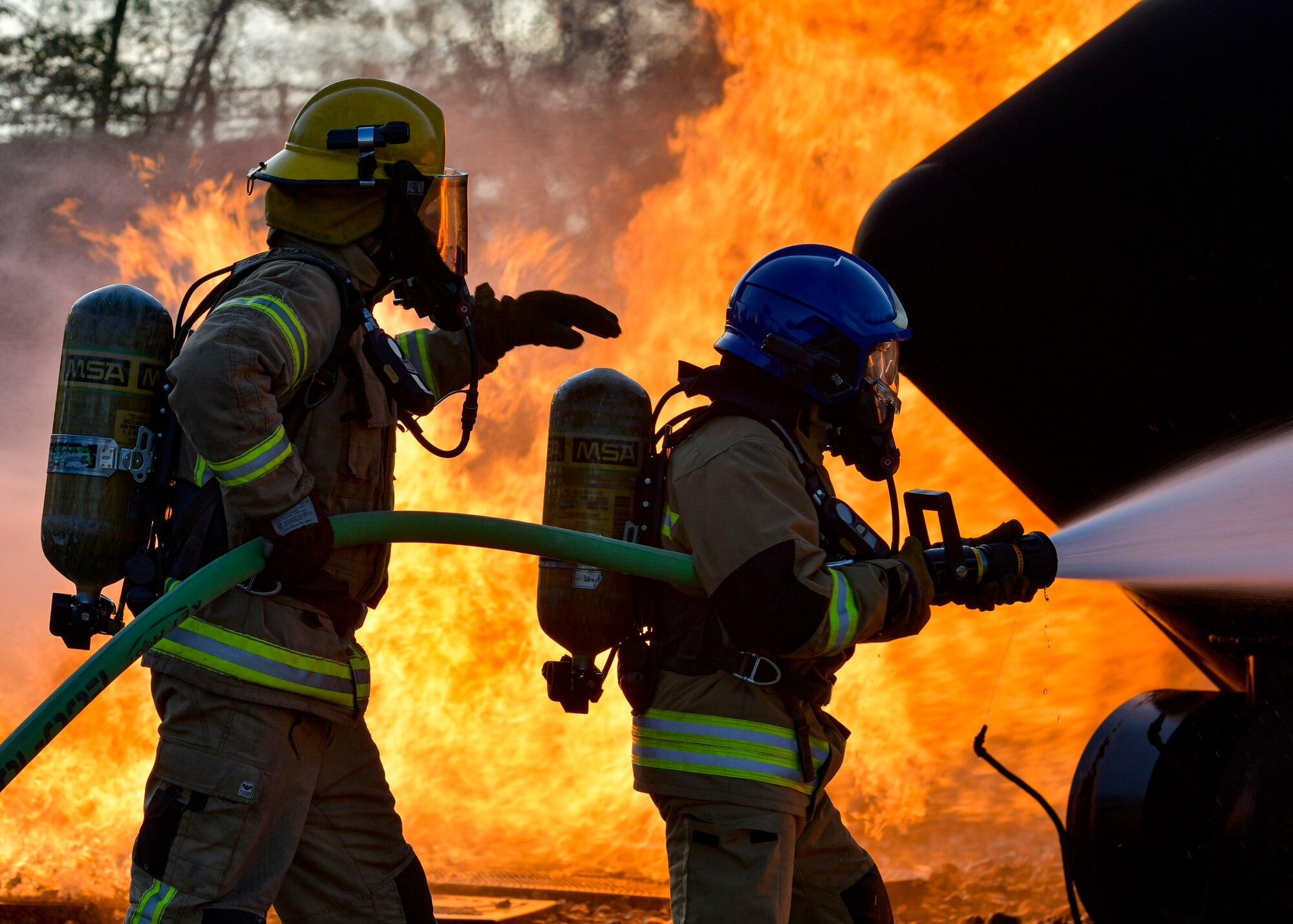 Firefighters with the Latvian National Armed Forces and Estonian Defense Forces use a fire hose to spray a simulated aircraft fire at Alpena Combat Readiness Training Center, Michigan, Aug. 12, 2021.