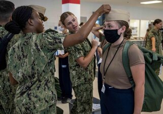220702-N-PW480-0164 GREAT LAKES, Ill. (July 2, 2022) A Naval Reserve Officers Training Corps (NROTC) New Student Indoctrination (NSI) 2022 Cycle 2 staff member assists an NSI midshipman candidate with proper cover fitting during uniform issue at Recruit Training Command (RTC), July 2. Upon completion of NSI, the candidates will start their freshman year of the NROTC program at colleges and universities nationwide this fall. NSI is an indoctrination program hosted at RTC, and provides midshipmen with a common military training orientation. NSI provides basic training in five warfighting fundamentals – firefighting, damage control, seamanship, watchstanding and small arms handling and marksmanship – to begin creating basically trained and smartly disciplined future Navy and Marine Corps officers. NROTC is overseen by Commander, Naval Service Training Command (NSTC), Rear Adm. Jennifer S. Couture, which supports naval accessions training for 98 percent of the Navy’s new officers and enlisted Sailors. (U.S. Navy photo by Mass Communication Specialist 2nd Class Nikita Custer)