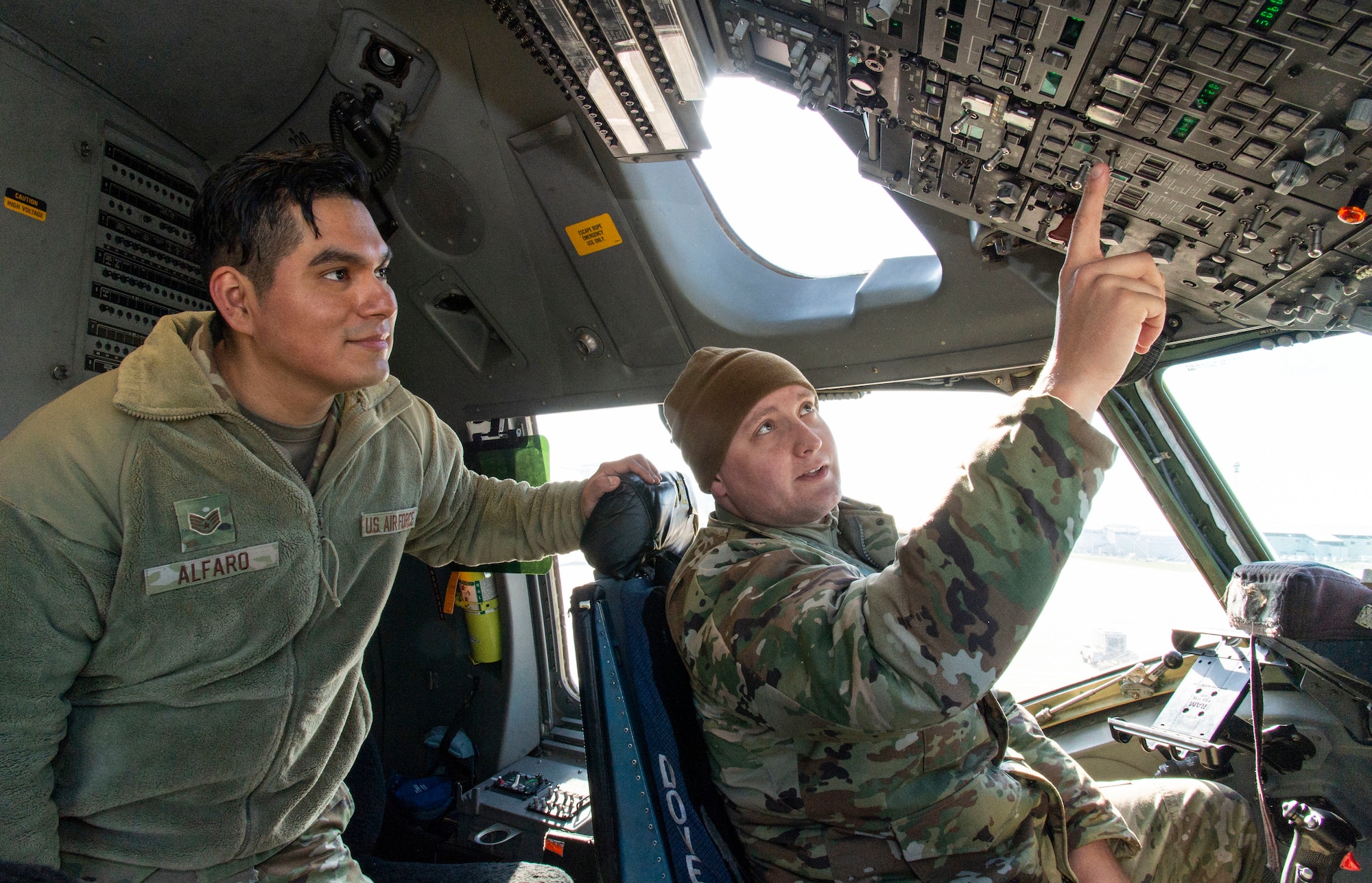 Staff Sgt. Renato Alfaro, left, 373rd Training Squadron, Detachment 3 C-17 aircraft general instructor, familiarizes Staff Sgt. Richard Watts, right, 436th Aerial Port Squadron load planner, with buttons on an overhead C-17 Globemaster III flight deck panel at Dover Air Force Base, Delaware, March 29, 2022. Alfaro provided Watts and other students participating in a multi-capable Airmen training class with basic C-17 aircraft familiarization. (U.S. Air Force photo by Roland Balik)