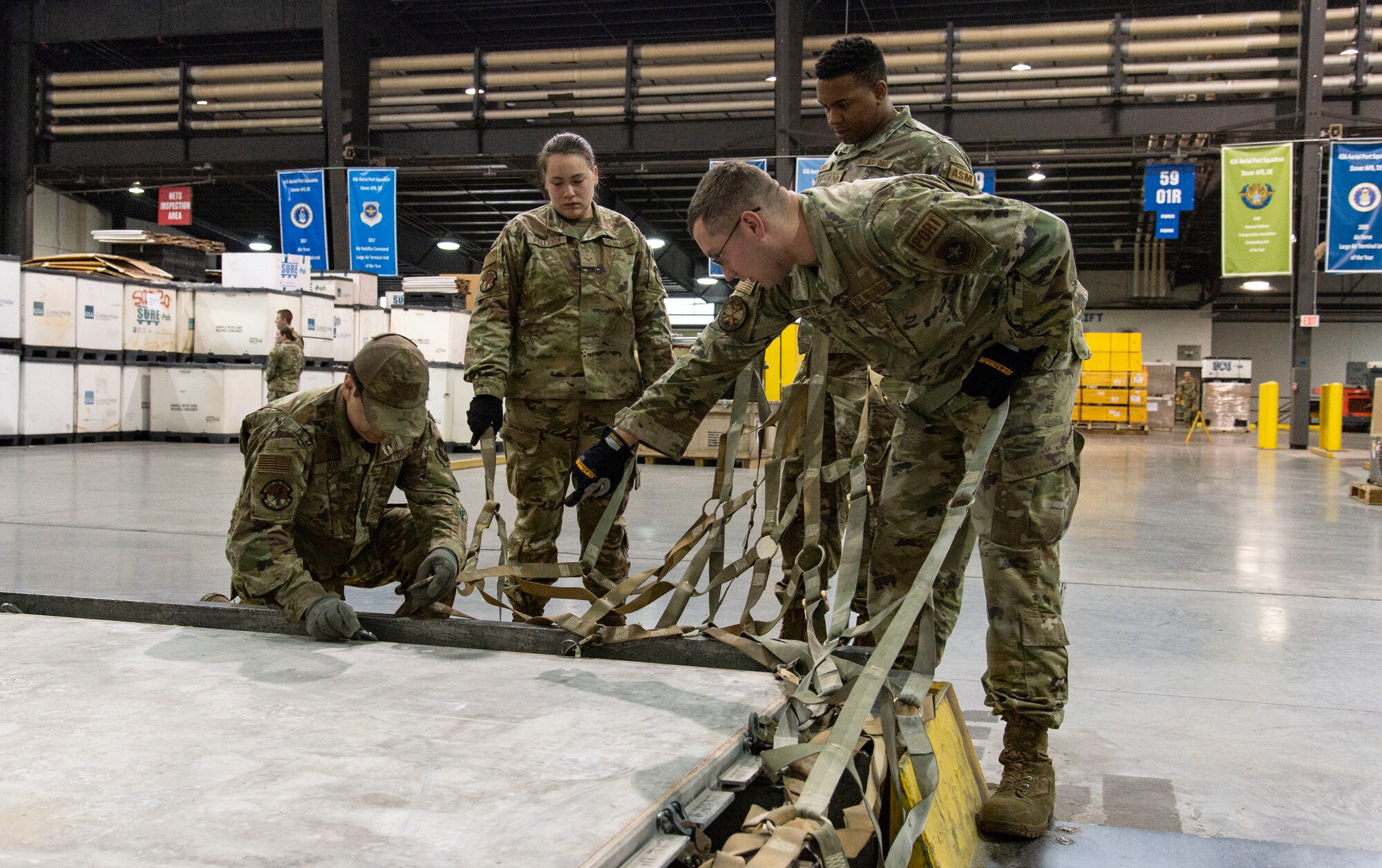 Students participating in a multi-capable Airman training class place cargo netting on a pallet at Dover Air Force Base, Delaware, March 31, 2022. Students received basic pallet building instructions and were assisted by 436th Aerial Port Squadron personnel. (U.S. Air Force photo by Roland Balik)