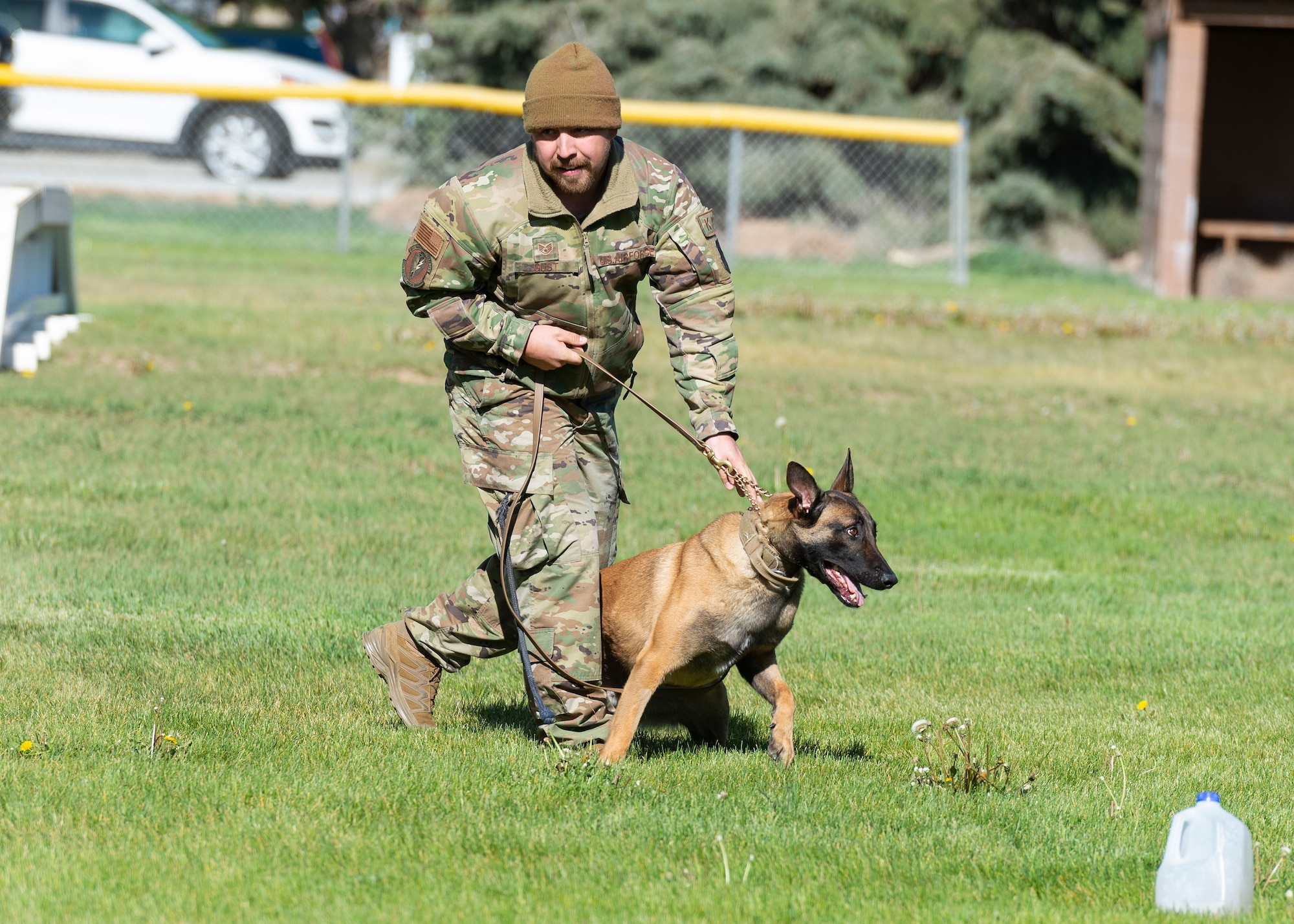 A military working dog handler, and his K-9, Yyankee, walk through the field.