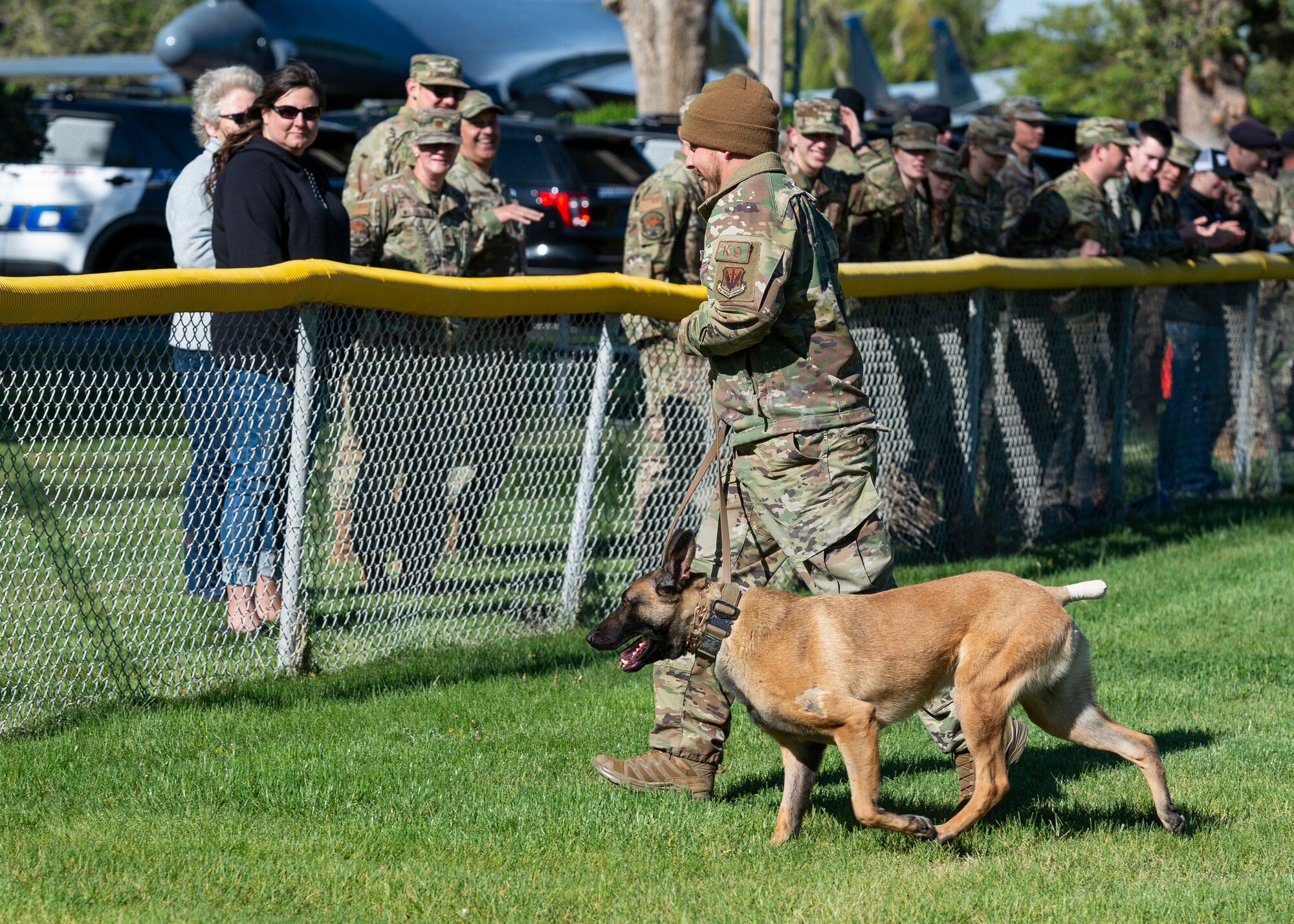 A military working dog handler, and his K-9, Yyankee, walk through the field.