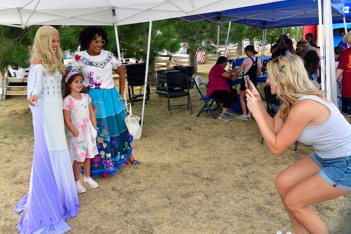 Cloe Taylor poses for a picture with Elsia and Marbella, played by Brooke Ballard and Veonka White, during the Military Salute Picnic held at Centennial Park Aug. 5, 2022, at Hill Air Force Base, Utah. The annual event is sponsored by the Top of Utah Military Affairs Committee and provided fun activities, free food and live entertainment for the base’s military and their families. (U.S. Air Force photo by Todd Cromar)