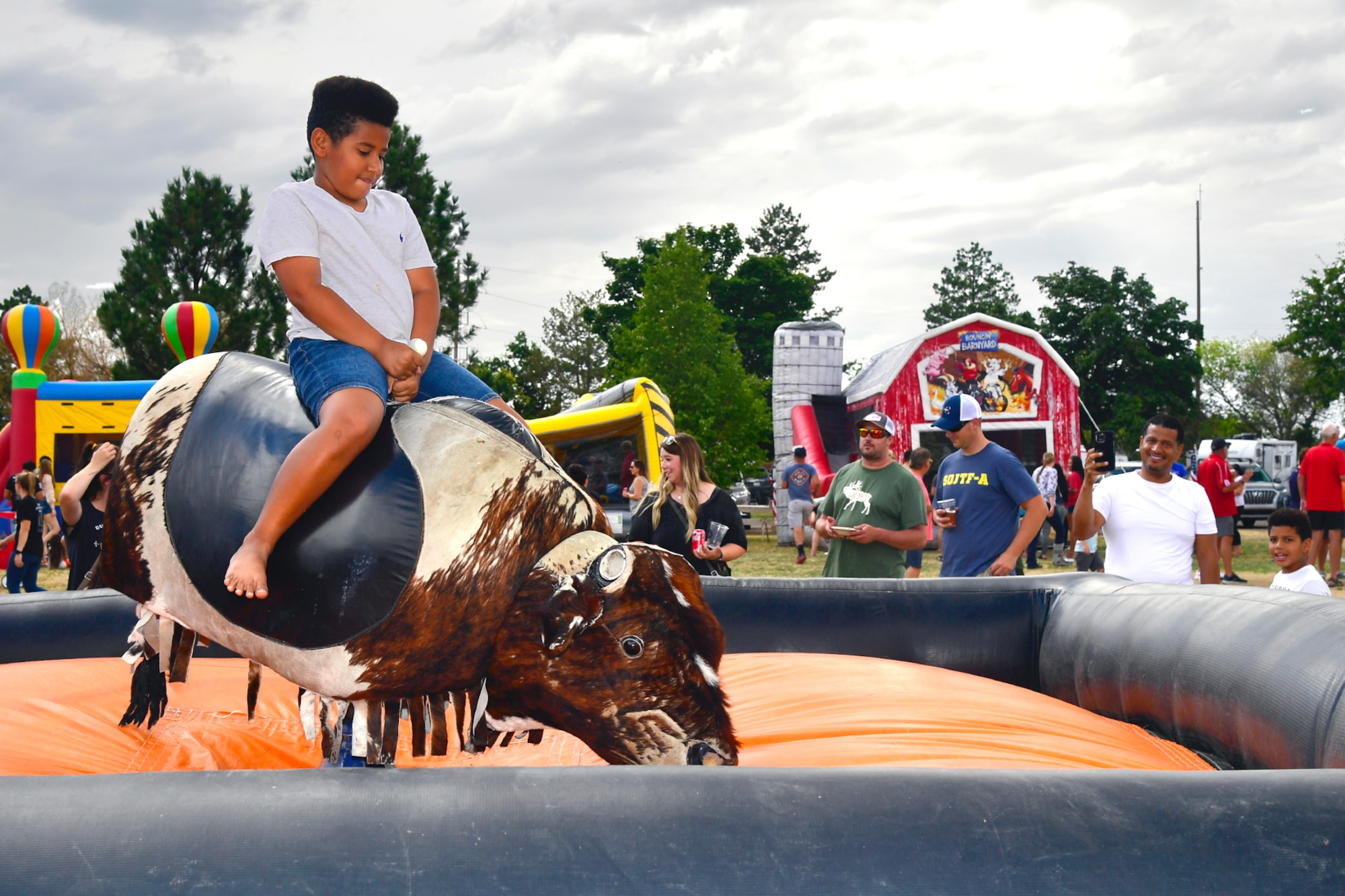 Visitor Evan Reynoso takes a turn on the mechanical bull during the Military Salute Picnic held at Centennial Park Aug. 5, 2022, at Hill Air Force Base, Utah. The annual event is sponsored by the Top of Utah Military Affairs Committee and provided fun activities, free food and live entertainment for the base’s military and their families. (U.S. Air Force photo by Todd Cromar)