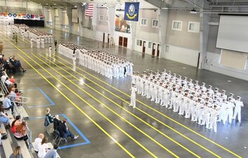 GREAT LAKES, Ill. (July 18, 2022) – Naval Reserve Officers Training Corps (NROTC) New Student Indoctrination (NSI) Cycle 2 midshipman candidates stand at parade rest during their graduation ceremony in the Midway Ceremonial Drill Hall at Recruit Training Command (RTC), July 18. Upon completion of NSI, the candidates will start their freshman year of the NROTC program at colleges and universities nationwide this fall. NSI is an indoctrination program hosted at RTC, and provides midshipmen with a common military training orientation. NSI provides basic training in five warfighting fundamentals – firefighting, damage control, seamanship, watchstanding and small arms handling and marksmanship – to begin creating basically trained and smartly disciplined future Navy and Marine Corps officers. NROTC is overseen by Commander, Naval Service Training Command (NSTC), Rear Adm. Jennifer S. Couture, which supports naval accessions training for 98 percent of the Navy’s new officers and enlisted Sailors. (U.S. Navy photo by Scott A. Thornbloom)