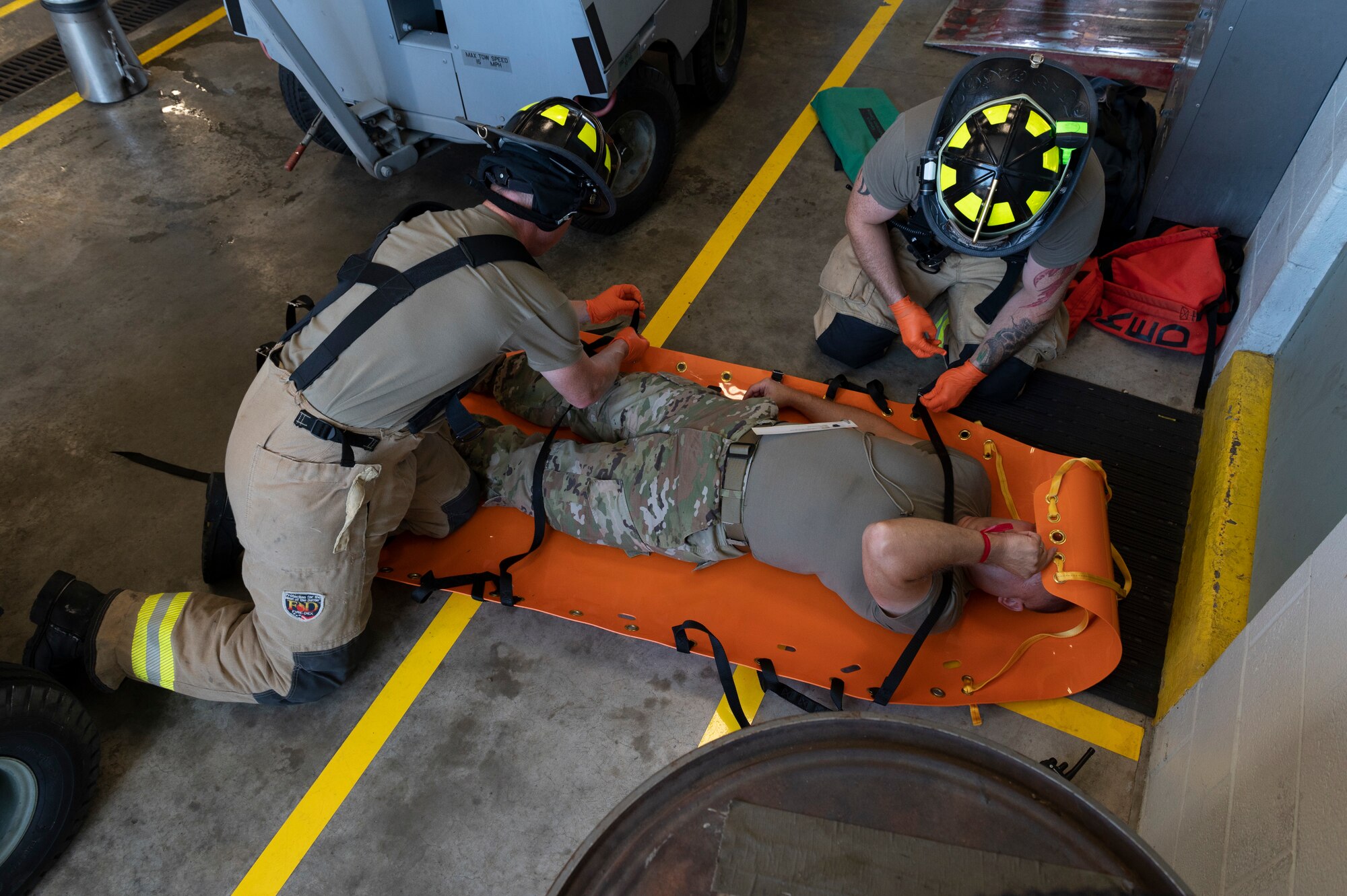 167th Airlift Wing Firefighters prepare a simulated victim to be moved during an active shooter simulation, at 167th Airlift Wing, Martinsburg, West Virginia, Aug. 7, 2022. Airmen with the 167th Airlift Wing participate in active shooter training scenarios annually, strengthening the coordination between security forces and firefighters.