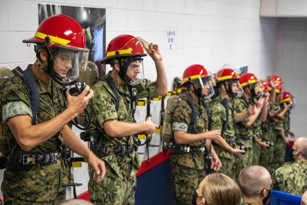 220728-N-PW480-0144 GREAT LAKES, Ill. (July 28, 2022) Naval Reserve Officers Training Corps (NROTC) New Student Indoctrination (NSI) 2022 Cycle 3 midshipman don firefighting equipment during a firefighting and damage control training exercise at Recruit Training Command (RTC), July 28. Upon completion of NSI, the candidates will start their freshman year of the NROTC program at colleges and universities nationwide this fall. NSI is an indoctrination program hosted at RTC, and provides midshipmen with a common military training orientation. NSI provides basic training in five warfighting fundamentals – firefighting, damage control, seamanship, watchstanding and small arms handling and marksmanship – to begin creating basically trained and smartly disciplined future Navy and Marine Corps officers. NROTC is overseen by Commander, Naval Service Training Command (NSTC), Rear Adm. Jennifer S. Couture, which supports naval accessions training for 98 percent of the Navy’s new officers and enlisted Sailors. (U.S. Navy photo by Mass Communication Specialist 2nd Class Nikita Custer)
