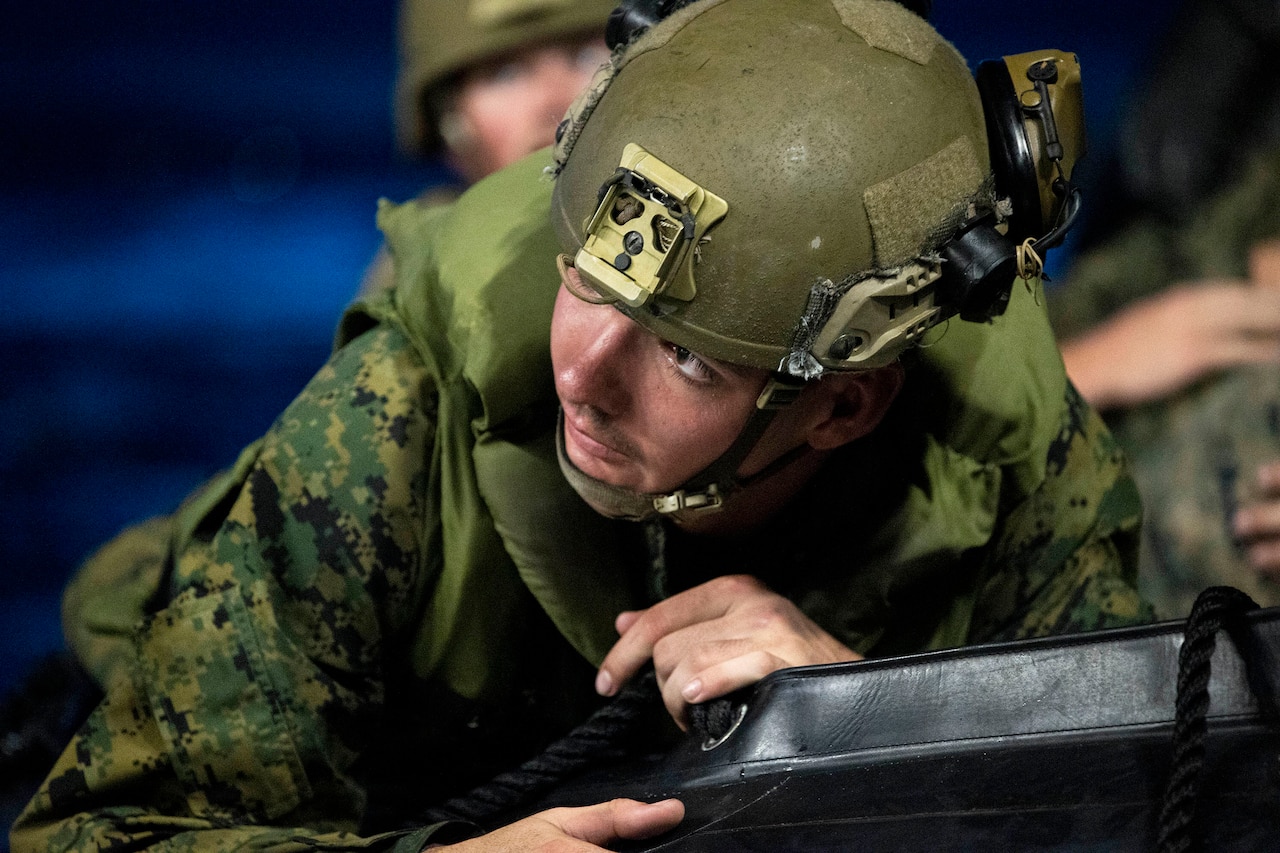 A Marine lies down on a rubber boat at night.