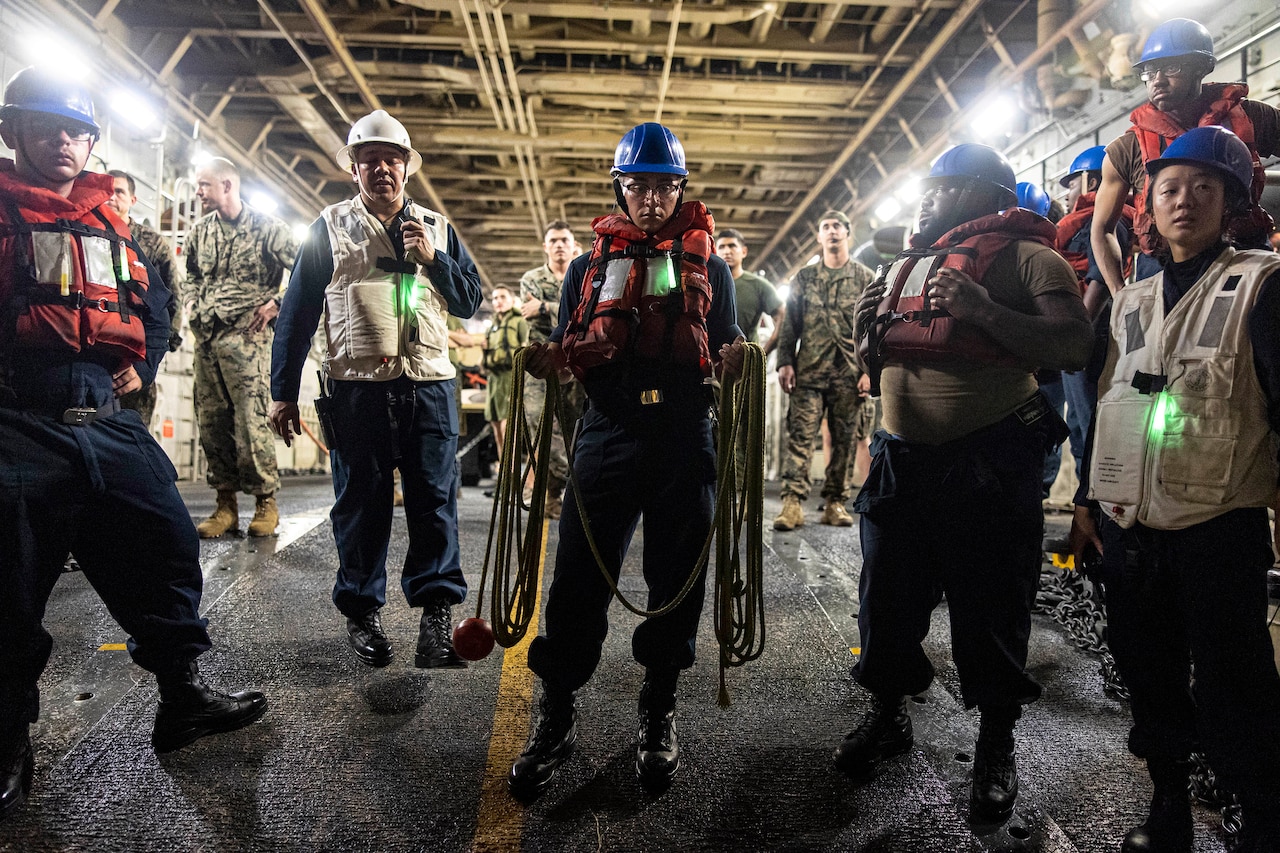 Sailors stand inside a ship.