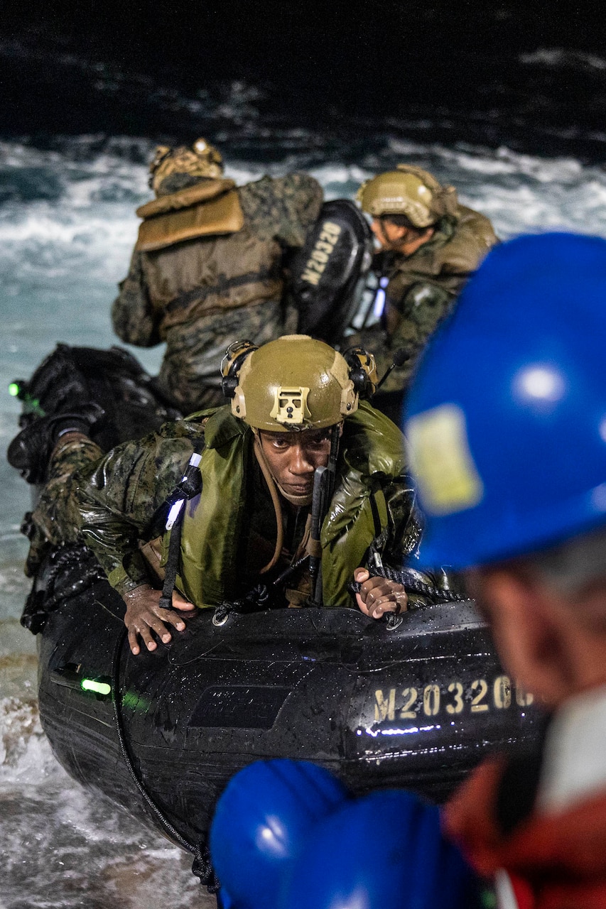 Marines in an inflatable boat in water approach ship deck.