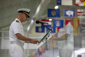GREAT LAKES, Ill. (Aug. 8, 2022) New Student Indoctrination (NSI) Cycle 3 Officer in Charge, Capt. John Compton, speaks during the graduation ceremony for Naval Reserve Officers Training Corps (NROTC) NSI Cycle 3 midshipman candidates inside the Midway Ceremonial Drill Hall at Recruit Training Command (RTC), August 8. The midshipmen will start their freshman year of the NROTC program at colleges and universities nationwide this fall. NSI is an indoctrination program hosted at RTC, and provides midshipmen with a common military training orientation. NSI provides basic training in five warfighting fundamentals – firefighting, damage control, seamanship, watchstanding and small arms handling and marksmanship – to begin creating basically trained and smartly disciplined future Navy and Marine Corps officers. NROTC is overseen by Commander, Naval Service Training Command (NSTC), Rear Adm. Jennifer S. Couture, which supports naval accessions training for 98 percent of the Navy’s new officers and enlisted Sailors. (U.S. Navy photo by Mass Communication Specialist 2nd Class Nikita Custer)