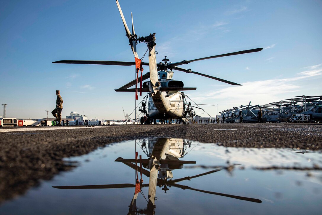 A Marine walks away from a parked helicopter.