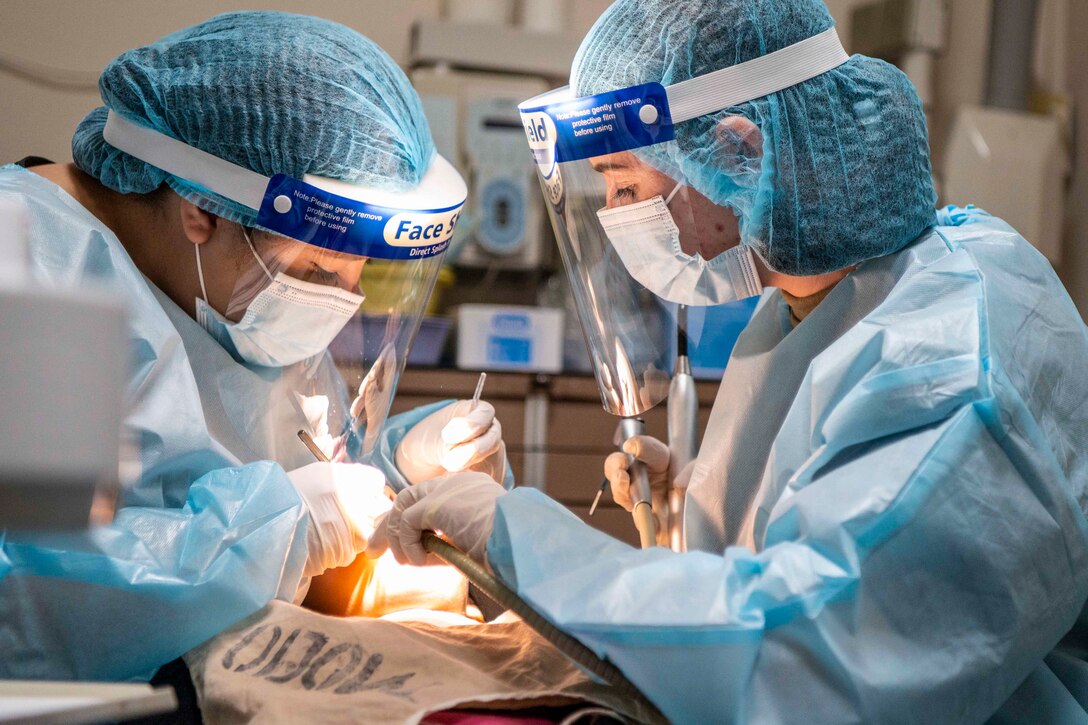 Two people wearing personal protective gear work on a patient.