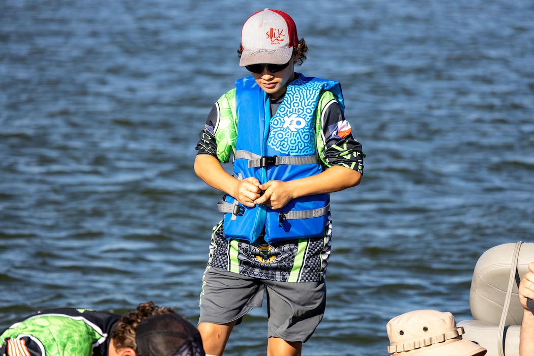 a kid puts on his lifejacket while on a boat