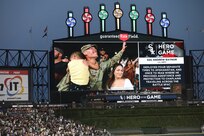 U.S. Army Reserve Staff Sgt. Andrew Raynor, with his son, Jacob, and wife Stacy, are cheered on a jumbotron during a ‘Hero of the Game’ honor at a Chicago White Sox versus Kansas City Royals game in Chicago, August 2, 2022.