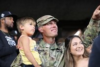 Staff Sgt. Andrew Raynor, holding his son, Jacob, and with his wife Stacy, waves to cheering fans while receiving an honor as the Hero of the Game at a Chicago White Sox home game, August 2, 2022.