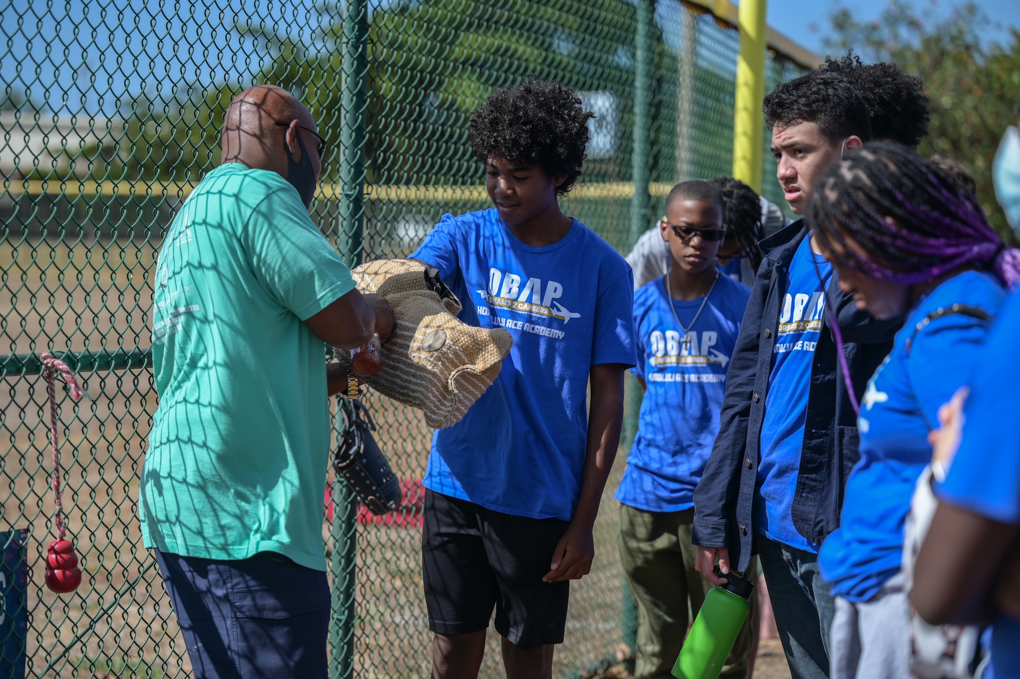 Visitors from the Organization of Black Aerospace Professionals Aerospace Career Education Academy try a bite sleeve during a military working dog demonstration at Joint Base Pearl Harbor-Hickam, Hawaii, July 28, 2022. Airmen assigned to the 647th Security Force Squadron performed detection and detainment training, demonstrating the MWD’s utilization and capabilities. (U.S. Air Force photo by Staff Sgt. Alan Ricker)