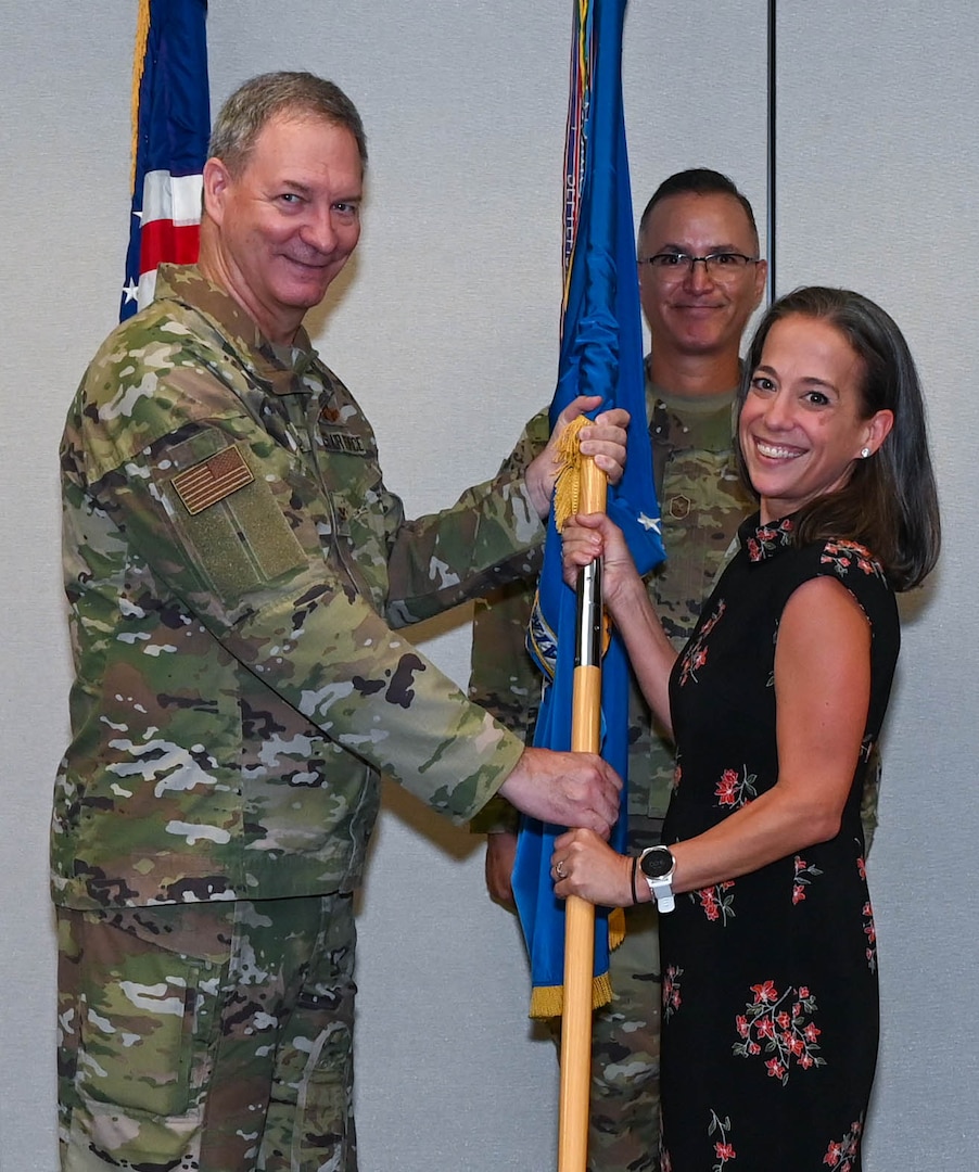 Col. Terry McClain, 433rd Airlift Wing commander, hands the 433rd AW guidon to Honorable Kirsten Cohoon, District Judge, 451st Judicial District Court judge, during a brief honorary commanders’ induction ceremony at Joint Base San Antonio-Lackland, Texas, Aug. 6, 2022. After the ceremony, honorary commanders toured the 433rd AW and witnessed demonstrations of virtual reality headset training alongside the C-5M Super Galaxy flight simulator. (U.S. Air Force photo by Airman 1st Class Mark Colmenares)