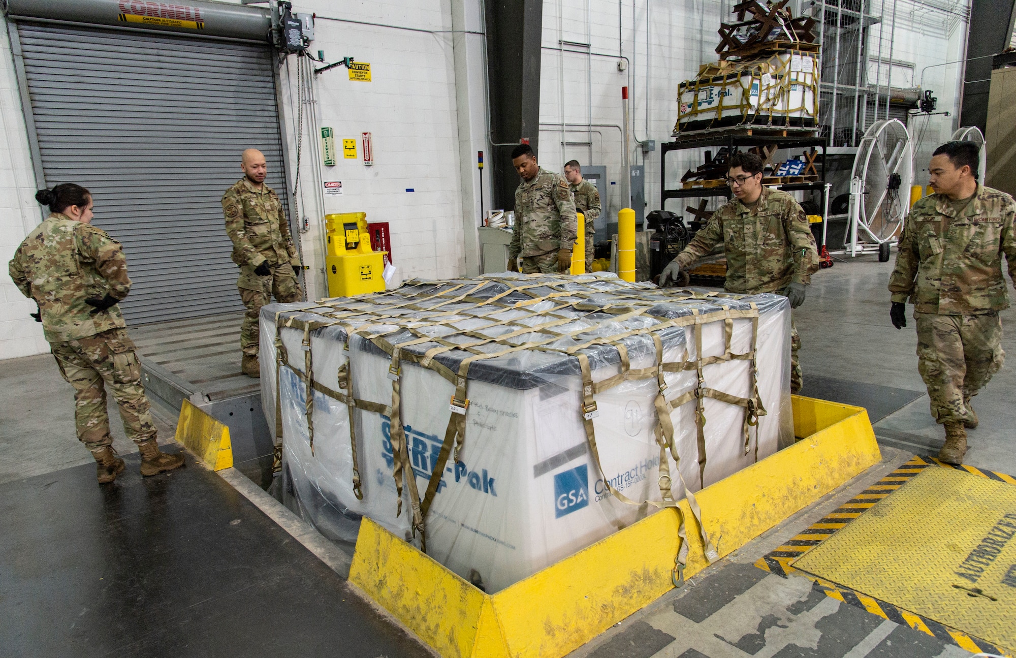 Students participating in a multi-capable Airman training class, place cargo netting on a pallet at Dover Air Force Base, Delaware, March 31, 2022. Students received basic pallet building instructions and were assisted by 436th Aerial Port Squadron personnel. (U.S. Air Force photo by Roland Balik)