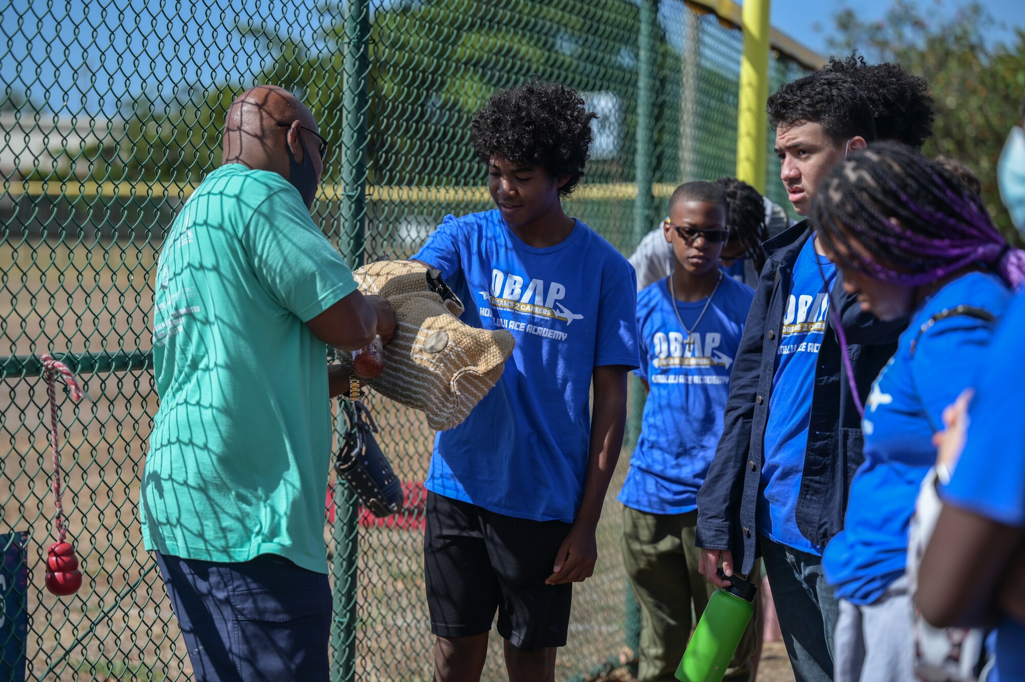 Visitors from the Organization of Black Aerospace Professionals Aerospace Career Education Academy try a bite sleeve during a military working dog demonstration at Joint Base Pearl Harbor-Hickam, Hawaii, July 28, 2022. Airmen assigned to the 647th Security Force Squadron performed detection and detainment training, demonstrating the MWD’s utilization and capabilities. (U.S. Air Force photo by Staff Sgt. Alan Ricker)