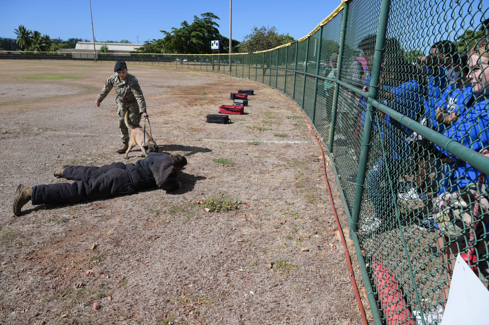 Airman 1st Class Christal Schaff, 647th Security Forces Squadron military working dog handler, and Ula, 647th SFS MWD, demonstrate detaining an aggressor portrayed by Staff Sgt. Jeremy Goff, 647th SFS MWD handler, during an Organization of Black Aerospace Professionals Aerospace Career Education Academy tour at Joint Base Pearl Harbor-Hickam, Hawaii, July 28, 2022. The academy learned how MWDs are trained in patrol work and specialize in different types of detection, such as patrol and drug recognition. (U.S. Air Force photo by Staff Sgt. Alan Ricker)