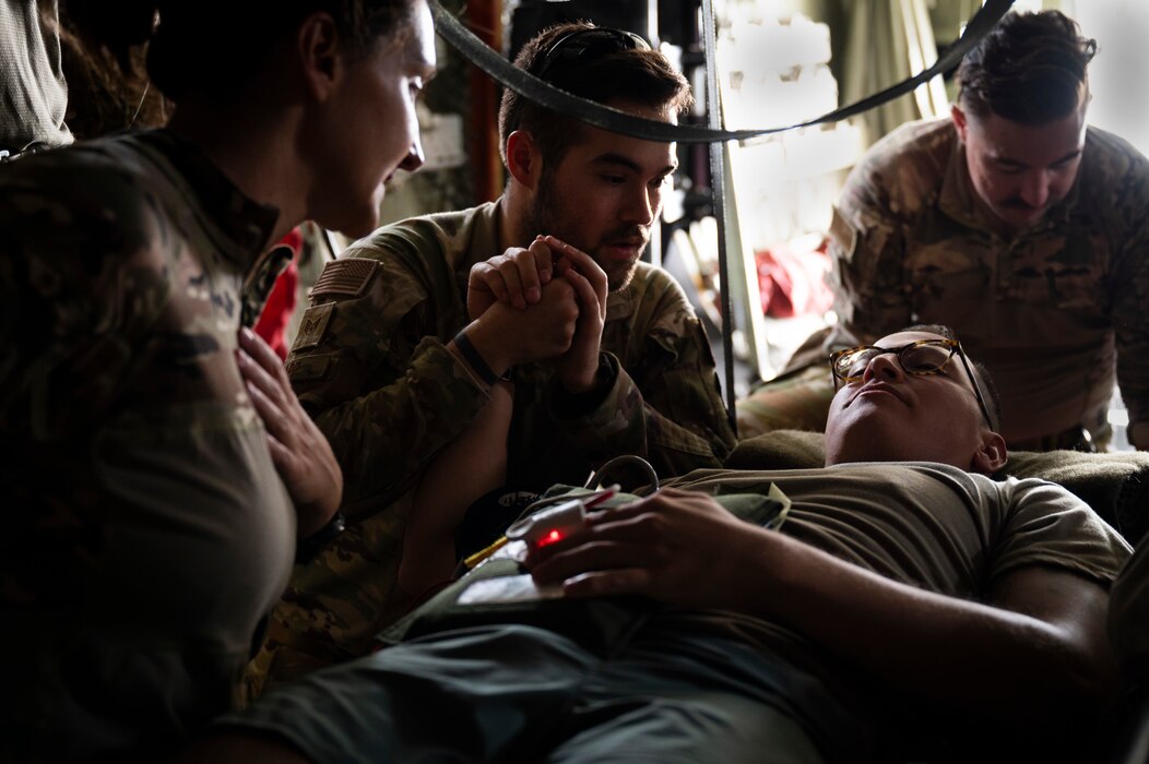 At right, U.S. Air Force Capt. Adam Escobedo, 405th Expeditionary Aeromedical Evacuation Squadron flight nurse, assists the coalition forces training exercise as a mock patient to be treated by the 405th Expeditionary Aeromedical Evacuation Squadron at Ali Al Salem Air Base, Kuwait, July 29, 2022. Coalition partners were able to learn and share tactics and techniques with each other so in an emergency response situation, the 405th EAES and coalition partners would be able to operate with the strength and coordination of one team. (U.S. Air Force photo by Staff Sgt. Dalton Williams)