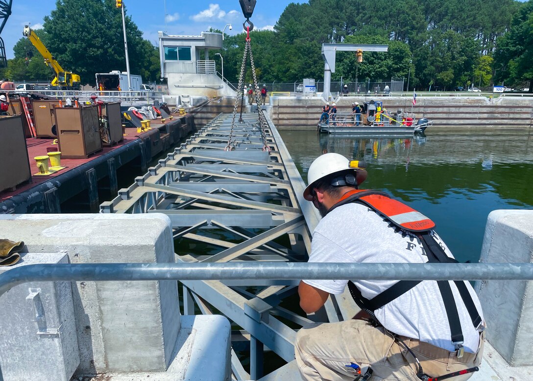 Huntington District engineer Gener Alvarado radios Nashville District divers underwater to ask how the stop log placement looks, before the team prepares the final stop log for placement at Cheatham Lock in Ashland City, TN.