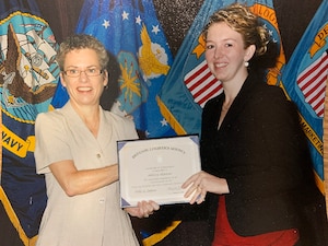 Two ladies stand with a certificate for photo