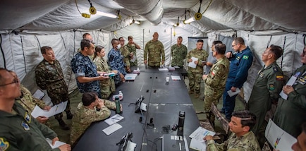 Military members from the U.S. and partner nation militaries conduct a briefing.