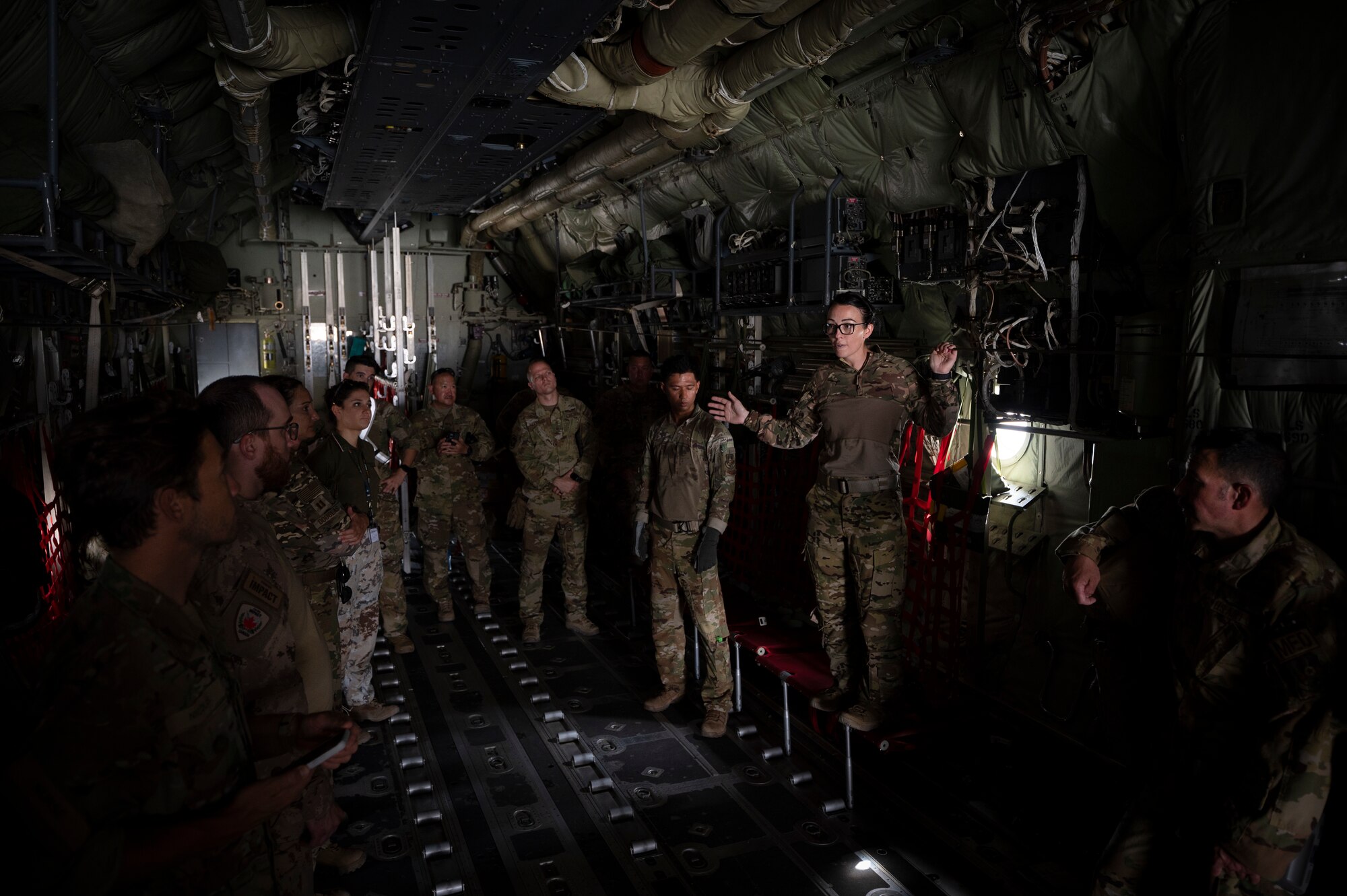 At right, U.S. Air Force Maj. Amanda Peterson, 405th Expeditionary Aeromedical Evacuation Squadron flight nurse, briefs Danish, Italian and Canadian coalition partners on how to configure and transport patients on U.S. Air Force aircraft at the flightline on Ali Al Salem Air Base, Kuwait, July 29, 2022. Coalition partners were able to learn and share tactics and techniques with each other so in an emergency response situation, the 405th EAES and coalition partners would be able to operate with the strength and coordination of one team. (U.S. Air Force photo by Staff Sgt. Dalton Williams)